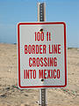 Sign at the US-Mexico Border on the Beach says, "100 FT BORDER LINE CROSSING INTO MEXICO"
