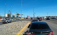 Baja - Mexicali - USA Border - Calexico II - Cars in left lane waiting to enter border complex, and others making left turns from the middle lane